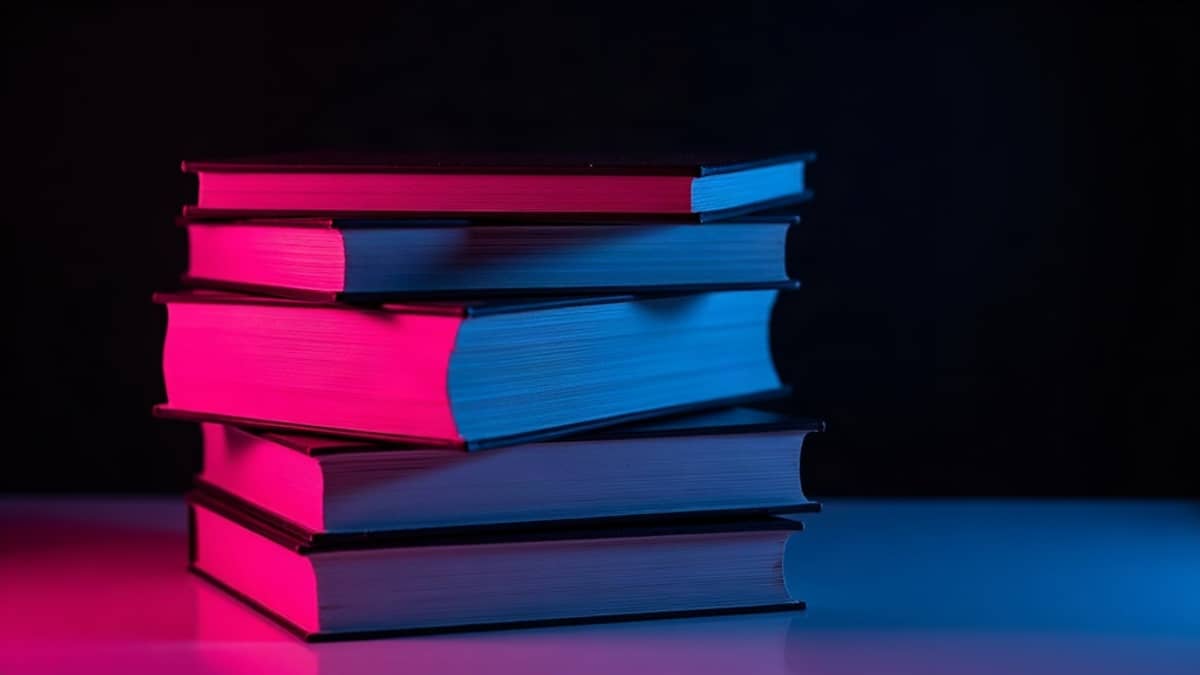 A stack of paperbacks lit in magenta and teal against a dark background